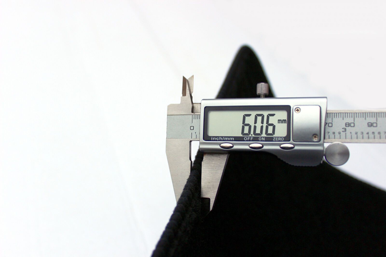 Messung der Stärke der Autofußmatte mit einer Schieblehre